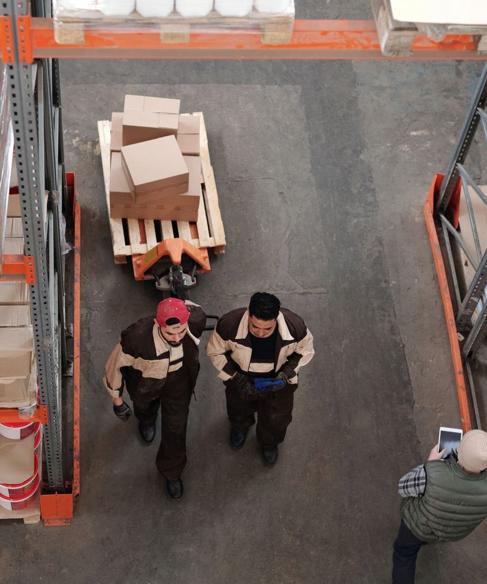 Warehouse team moving a pallet of boxes between racks