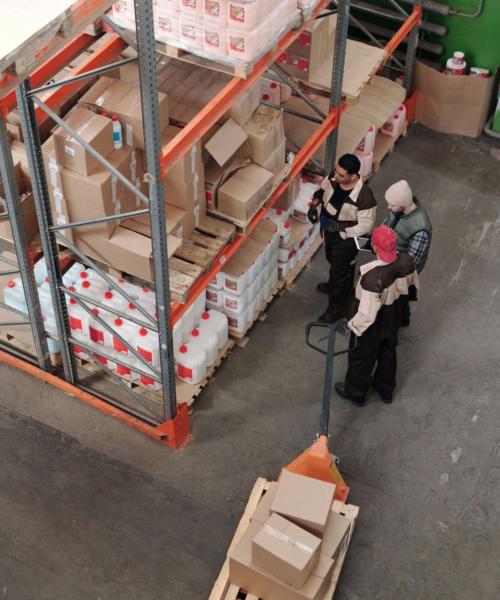 Warehouse team checking inventory together beside the racks